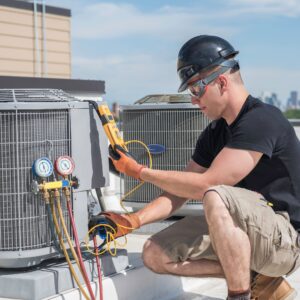 HVAC Technician on roof testing AC unit in summer